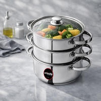 Stack of stainless steel steamer pots with vegetables on a gray surface